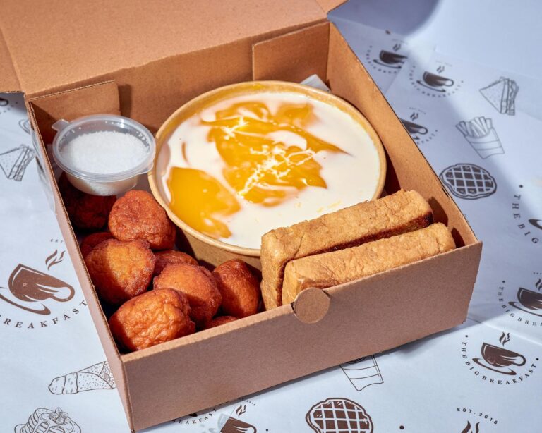 A boxed breakfast featuring akara, pap, and bread for a hearty Nigerian meal.