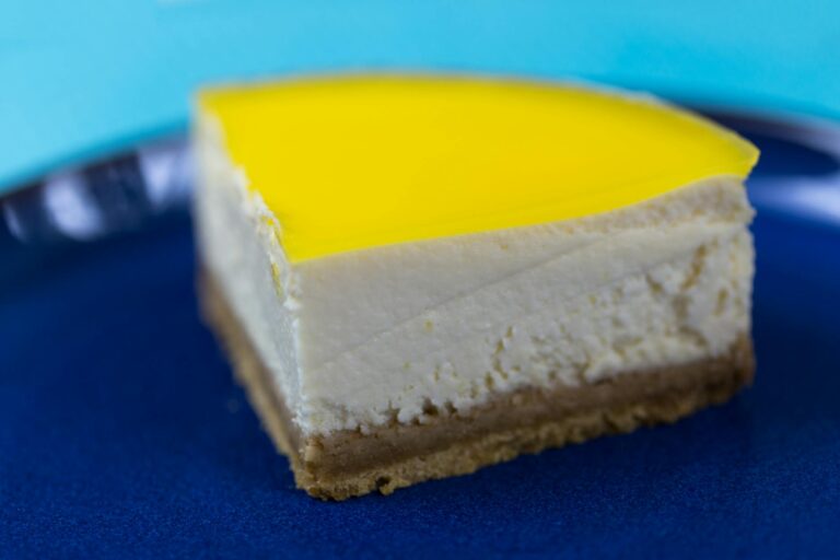 A close-up of a creamy lemon cheesecake slice on a vibrant blue plate. Perfect for food lovers.