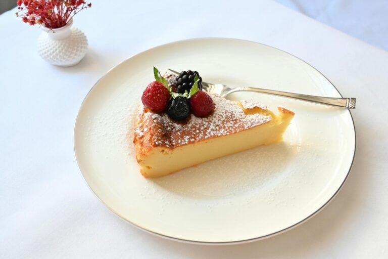 A tempting slice of cheesecake with fresh berries on a white plate, perfect for dessert.