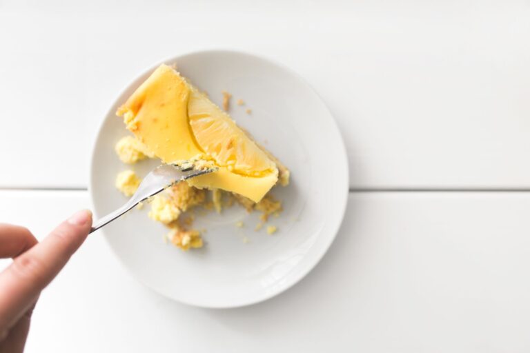 A tempting slice of creamy cheesecake on a white plate, ready to eat.